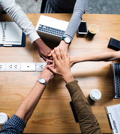 Five hands touching over an office desk