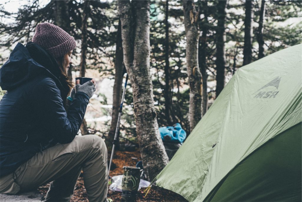 Girl camping outdoors while holding a drink